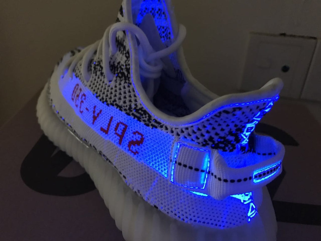 Yeezy 350 V2 Glow-in-the-Dark Sneakers, in Black and White - product image from the listing.