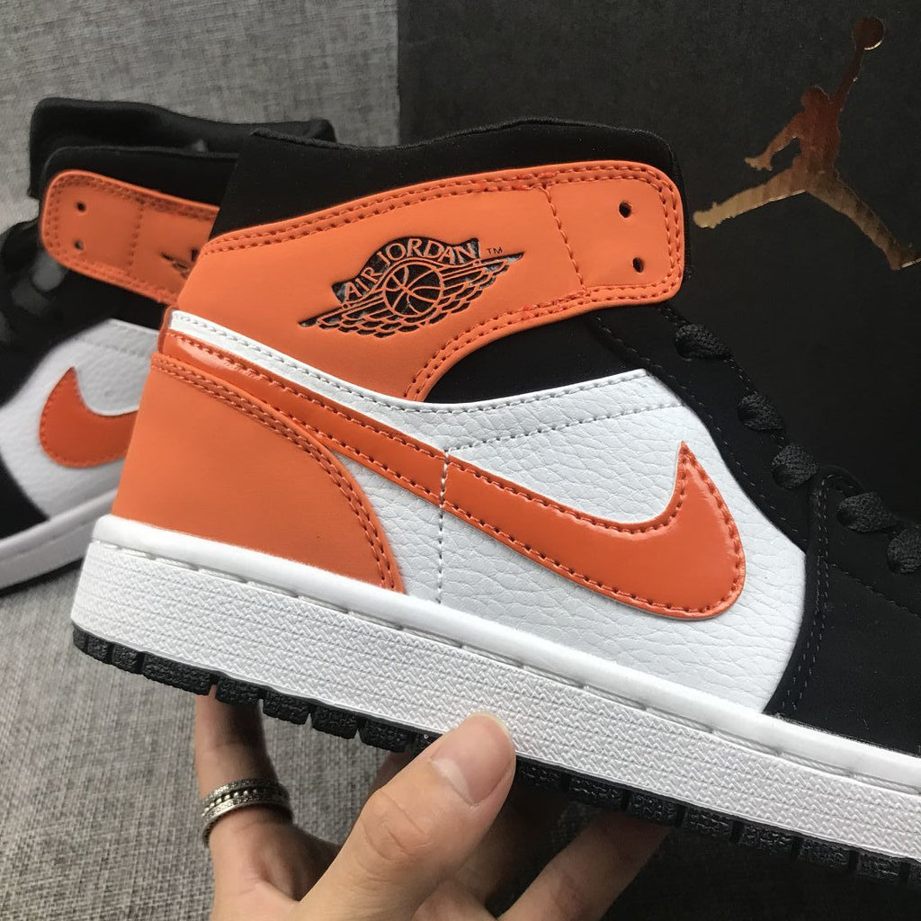 Air Jordan 1 Mid Sneakers in Black White Orange 554724-058 - product image from the listing.
